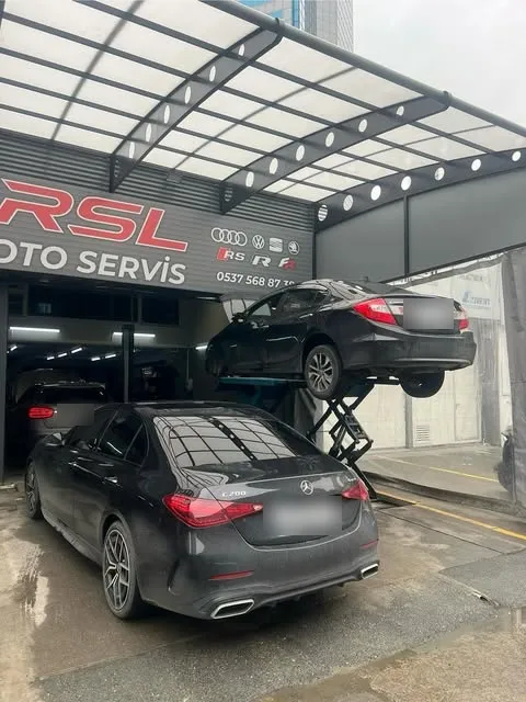 Atölye girişi, makaslı liftte bir sedan